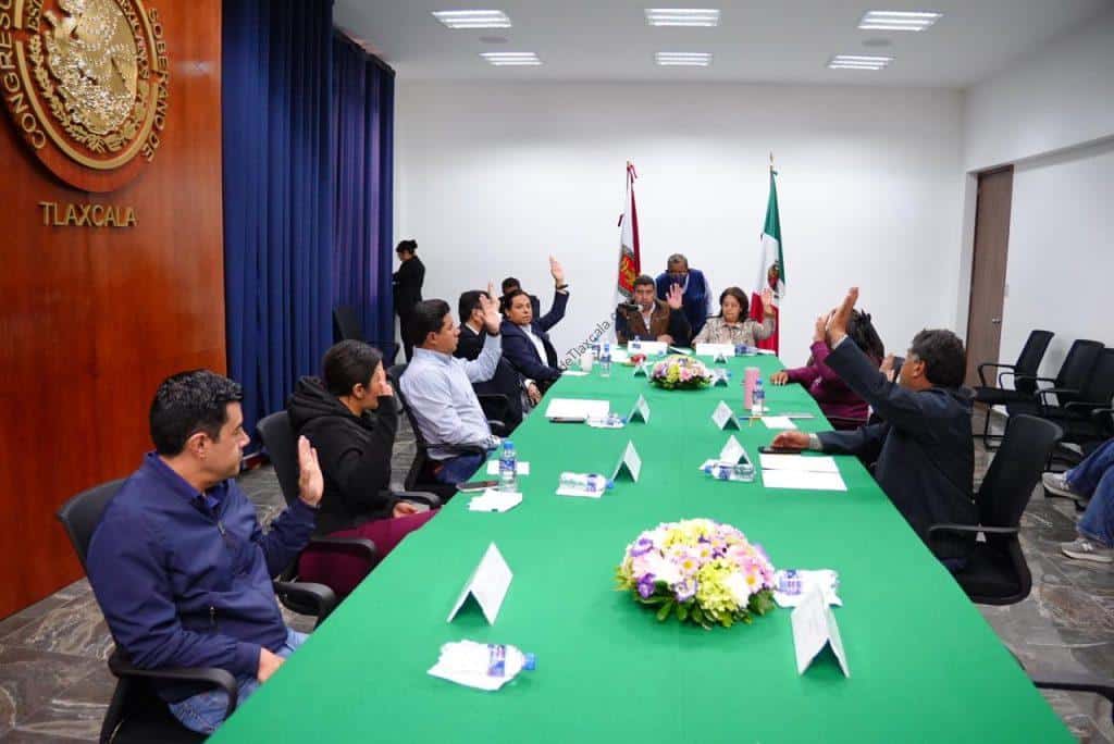 Reunión oficial en Tlaxcala con funcionarios y representantes, discutiendo temas importantes en un ambiente formal y colaborativo.