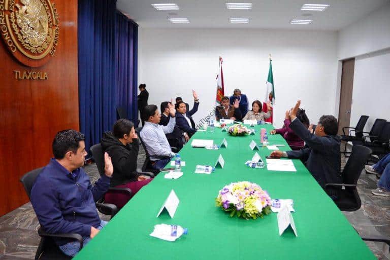 Reunión oficial en Tlaxcala con funcionarios y representantes, discutiendo temas importantes en un ambiente formal y colaborativo.