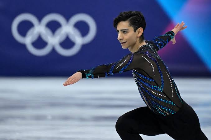 Patinador artístico en los Juegos Olímpicos con fondo de los anillos olímpicos.