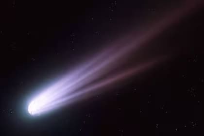 Cometa con cola brillante en el espacio, iluminando la oscuridad con su estela luminosa y difusa.