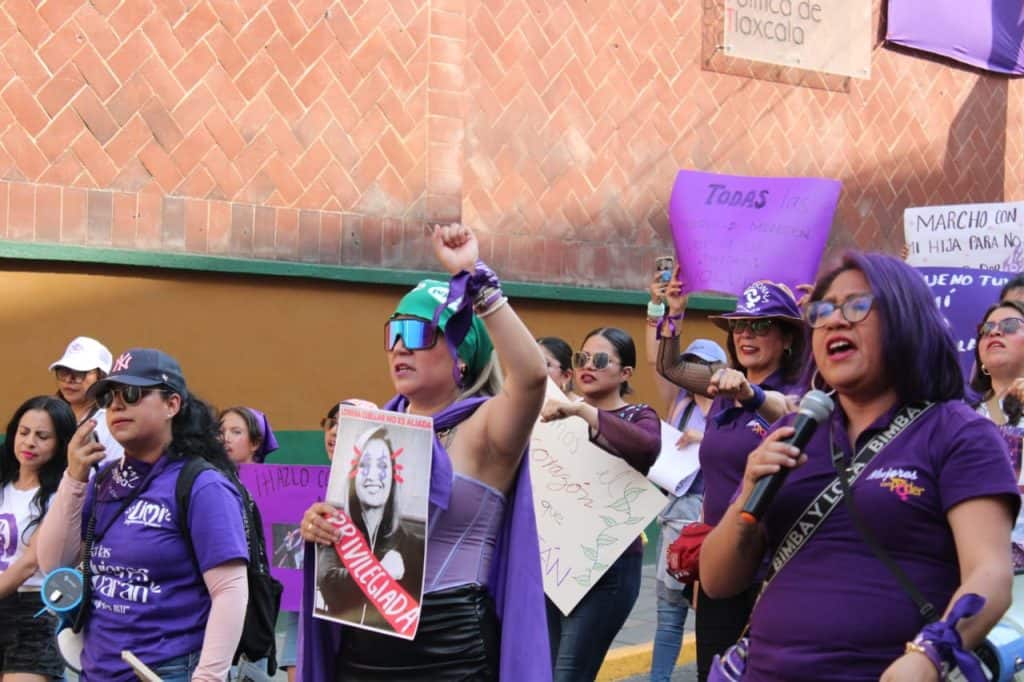 Asesinato de mujer en marcha feminista en Tlaxcala, manifestantes con carteles y megáfono en protesta.