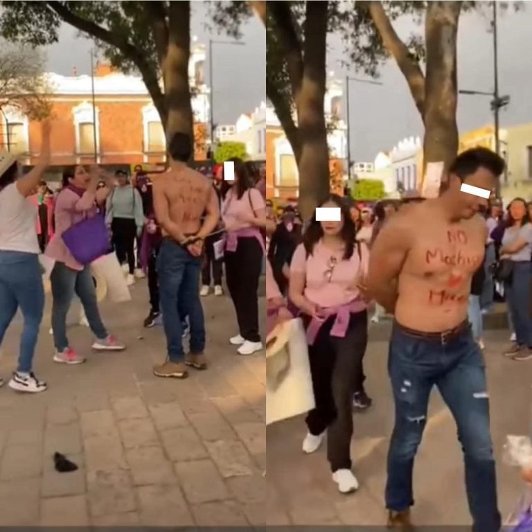 Persona desnuda con mensaje escrito en el torso en una manifestación en Tlaxcala, rodeada de personas con ropa casual y árboles en el fondo.