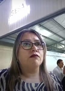 Mujer con gafas y cabello largo en un entorno de interior, posiblemente en un evento o conferencia en Tlaxcala, México.