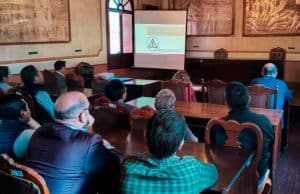 Capacitación sobre seguridad y protección civil en un salón de eventos históricos en Tlaxcala, con asistentes atentos a la presentación proyectada en pantalla.