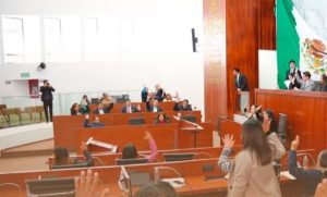 Voto en una sesión del Congreso de Tlaxcala con legisladores levantando la mano para votar.