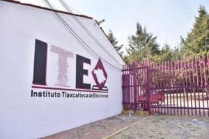 Fachada del Instituto Tlaxcalteca de Elecciones con muro y portón rosa en Tlaxcala, México.