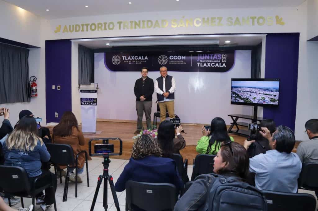 Auditorio Trinidad Sánchez en Tlaxcala, donde dos personas presentan un evento frente a una audiencia, con pantallas y equipo audiovisual en un espacio moderno y bien equipado.