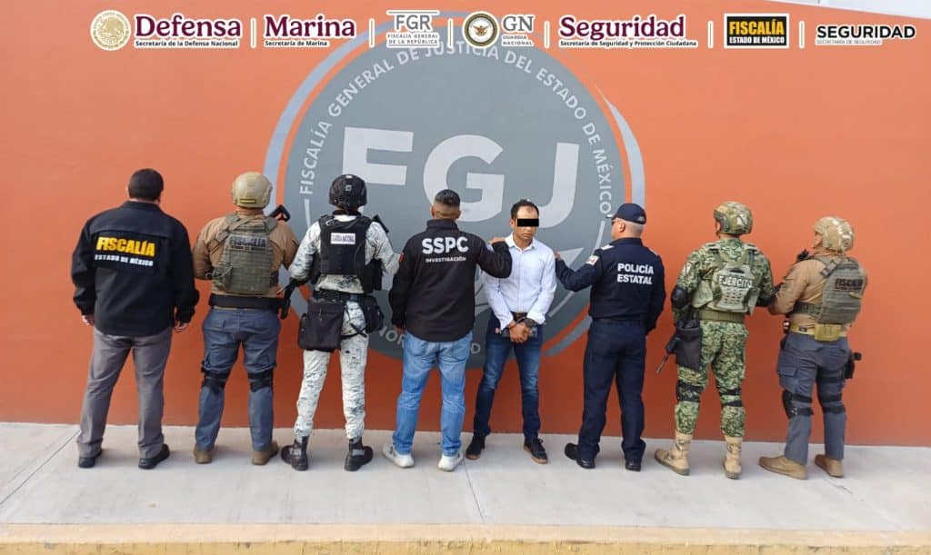 Grupo de oficiales y agentes de seguridad en una conferencia frente a un muro con logotipos oficiales en Tlaxcala, México.
