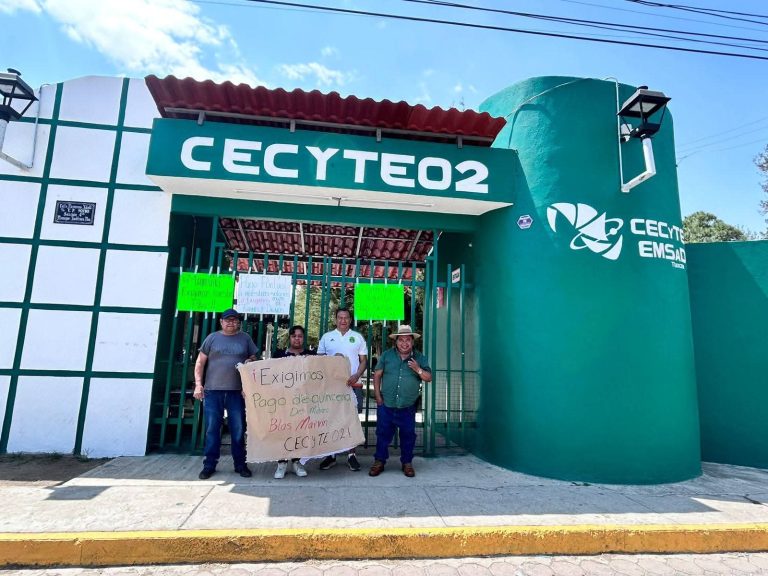 Grupo de personas protestando frente a la entrada del CECYTE 02 en Tlaxcala, sosteniendo un cartel y manifestando sus demandas educativas.