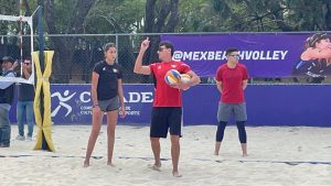 Jugadores de voleibol de playa en una competencia, con un árbitro y espectadores en el fondo, en un torneo al aire libre en Tlaxcala.