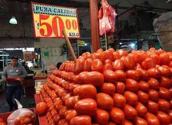 Pila de tomates rojos frescos en un mercado, con cartel que indica "Pura Calidad 50.00 Kilo".