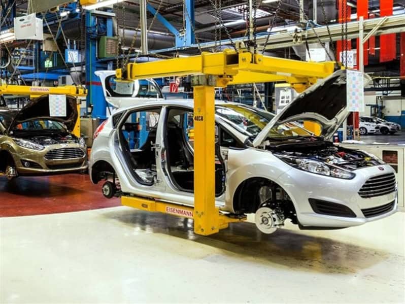 Mecánico inspeccionando un automóvil en una línea de ensamblaje en una fábrica de autos.