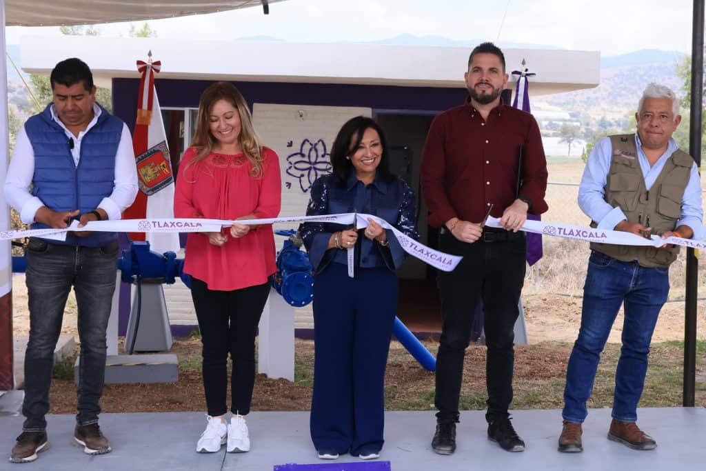 Personas participando en una ceremonia de inauguración en Tlaxcala, México, con una cinta de apertura y banderas oficiales en un evento al aire libre.