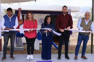 Personas participando en una ceremonia de inauguración en Tlaxcala, México, con una cinta de apertura y banderas oficiales en un evento al aire libre.