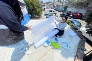 Parece que la imagen muestra a dos personas trabajando en la colocación de un material transparente en un área exterior, posiblemente para protección o decoración.