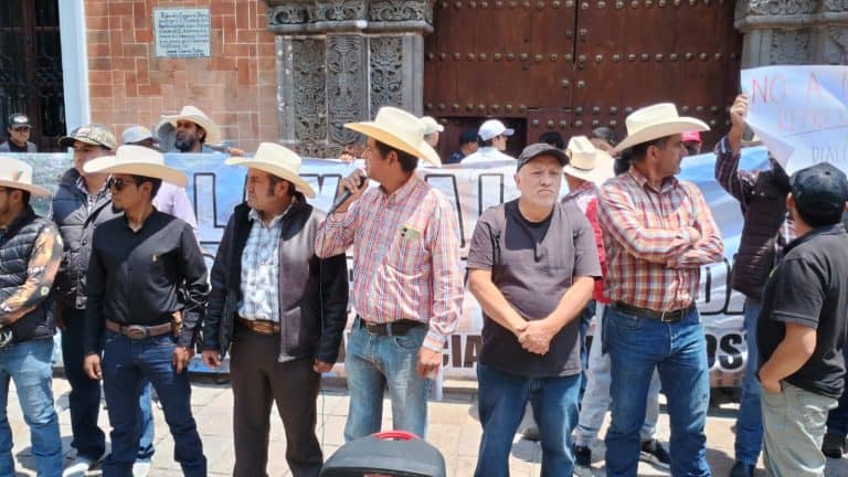 Manifestantes en una protesta pacífica frente a un edificio histórico en Tlaxcala, portando carteles y sombreros de ala ancha, exigiendo justicia y derechos sociales en una manifestación ciudadana.