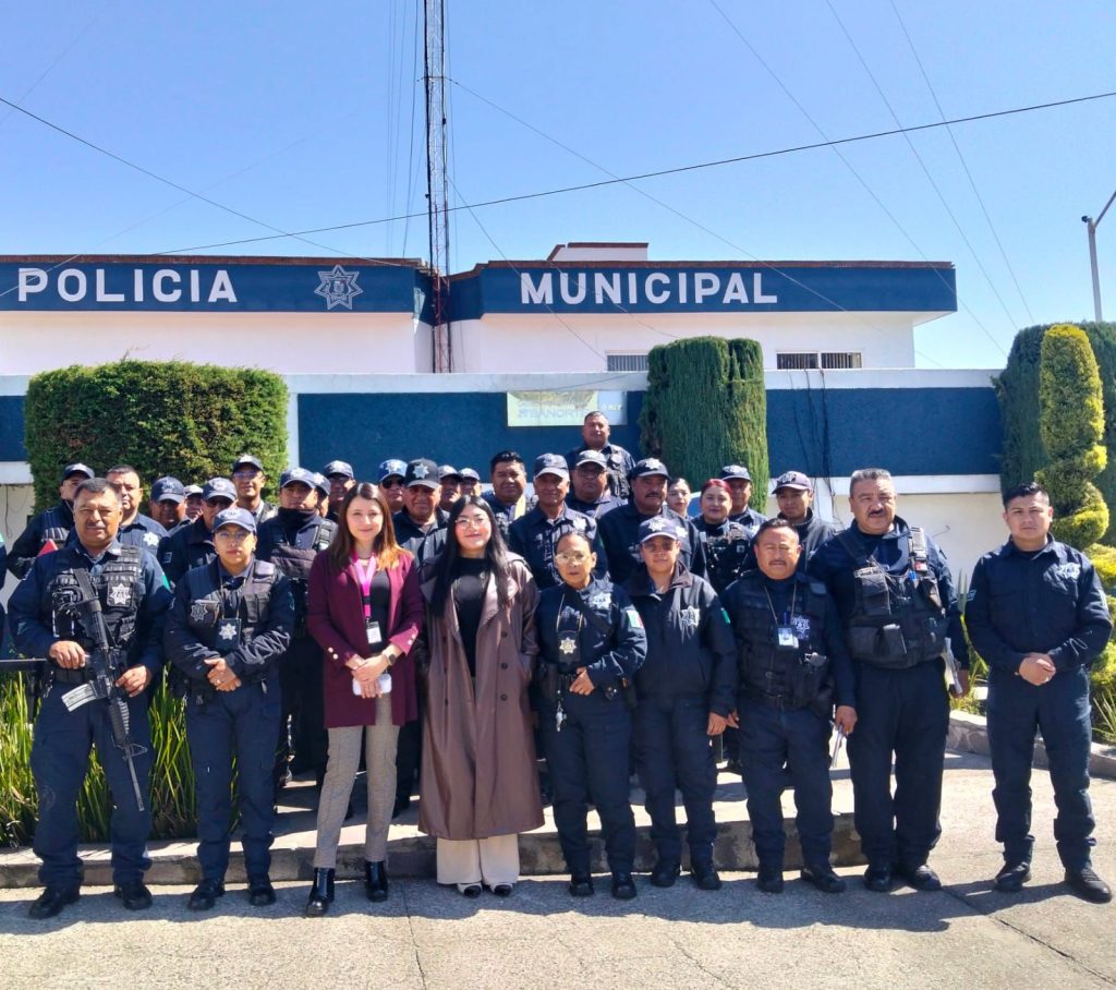 Policías municipales y personal civil posando frente a la estación de policía en Tlaxcala, México, durante una ceremonia o evento oficial.