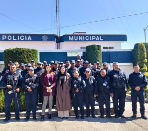 Policías municipales y personal civil posando frente a la estación de policía en Tlaxcala, México, durante una ceremonia o evento oficial.