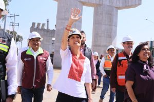 Grupo de funcionarios y trabajadores en una visita de inspección en una obra de infraestructura en Tlaxcala, con estructura de concreto en construcción y cielo despejado.