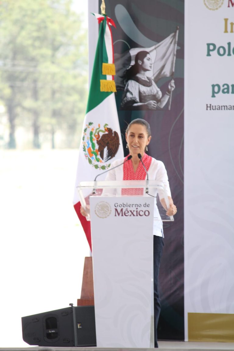Mujer hablando en un podio con bandera de México al fondo en un evento oficial.