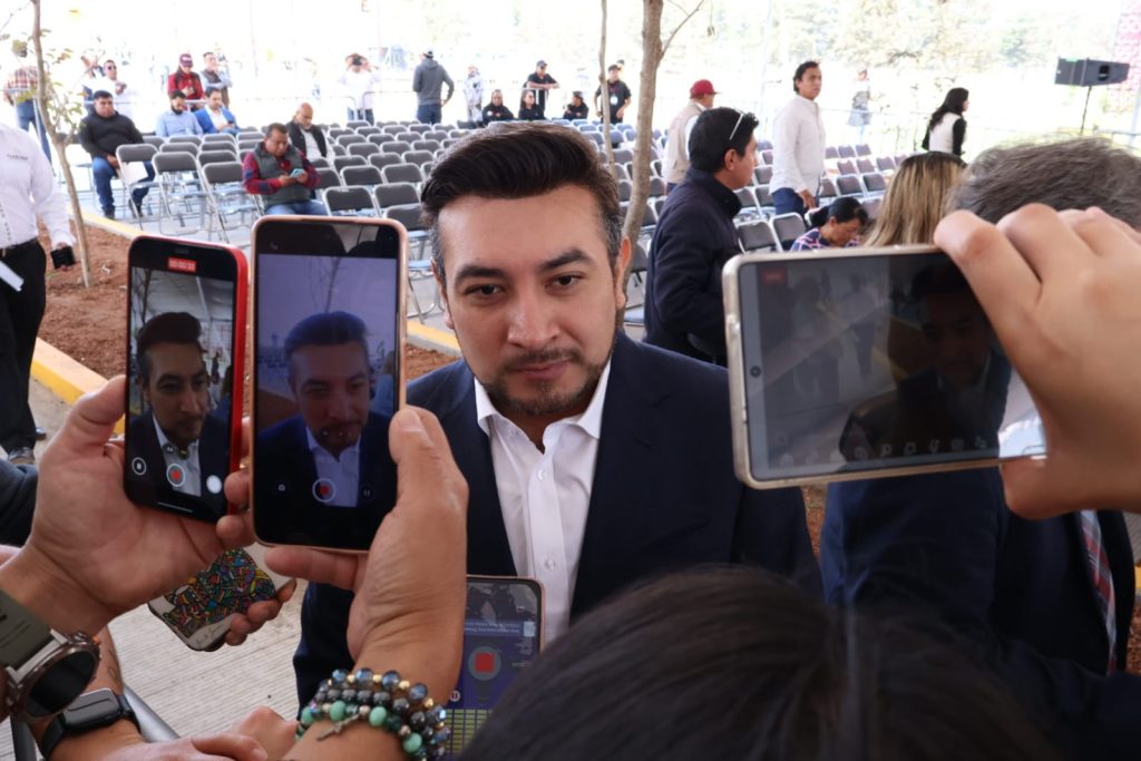 Hombre en entrevista siendo grabado por múltiples teléfonos en un evento al aire libre.