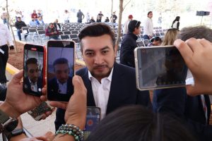 Hombre en entrevista siendo grabado por múltiples teléfonos en un evento al aire libre.