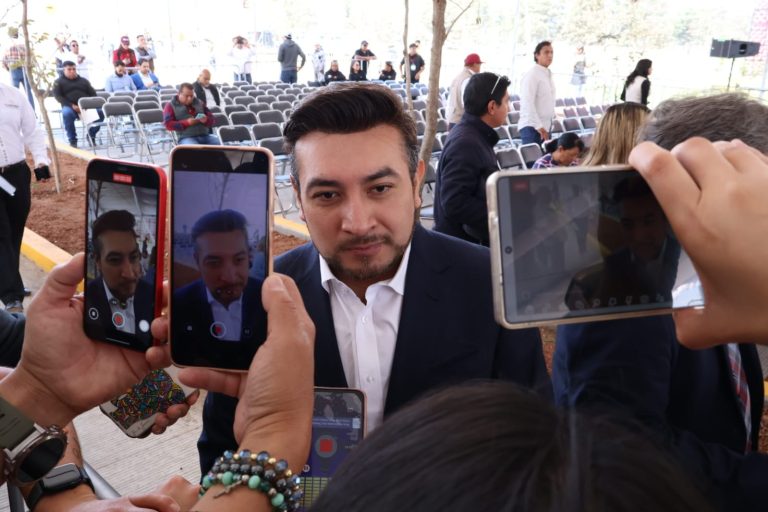 Hombre en entrevista siendo grabado por múltiples teléfonos en un evento al aire libre.