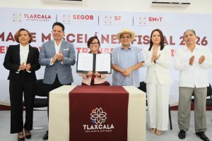 Grupo de seis personas en una ceremonia oficial en Tlaxcala, firmando un acuerdo o documento importante, con fondo de logotipos institucionales y texto en español.