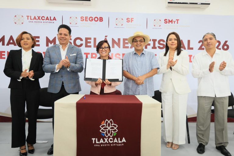 Grupo de seis personas en una ceremonia oficial en Tlaxcala, firmando un acuerdo o documento importante, con fondo de logotipos institucionales y texto en español.
