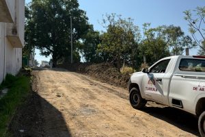 La camioneta de la autoridad de Tlaxcala estacionada en una calle de tierra en un área rural, con árboles y un cielo despejado en el fondo.