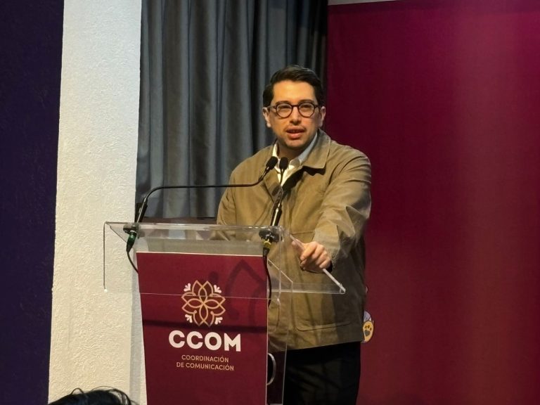 Hombre hablando en un podio durante una conferencia o evento formal en un entorno interior.