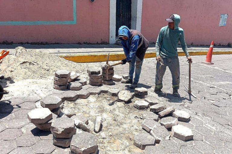 Reparación de pavimento en calle de Tlaxcala con trabajadores colocando adoquines en una vía pública.