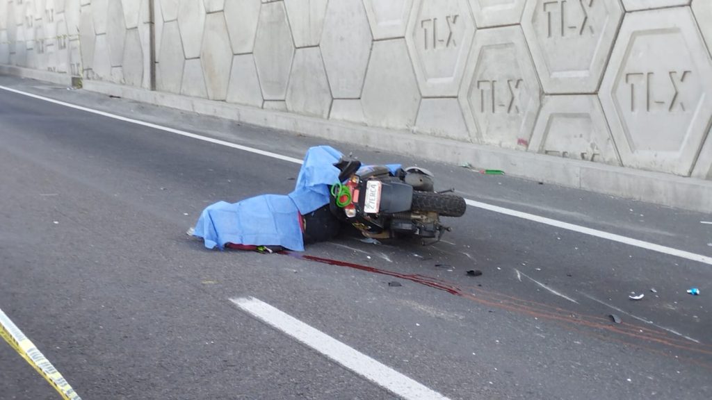 Accidente de motocicleta en la carretera, con la moto caída y daños visibles, en un día soleado.