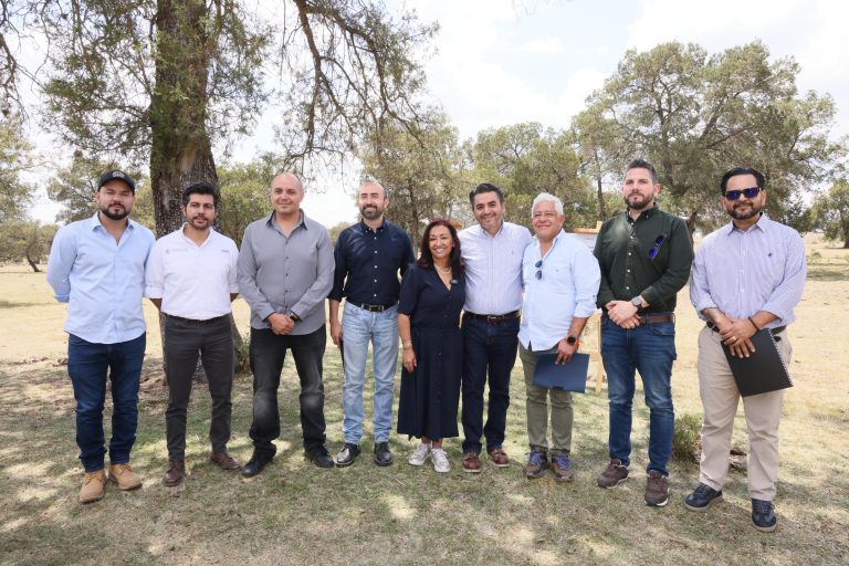 Personas en una reunión al aire libre, posando para la foto en un entorno natural con árboles y césped.