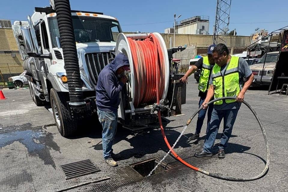 Técnicos reparando una fuga en la calle con equipo especializado y una manguera de gran tamaño en un día soleado en Tlaxcala, México.