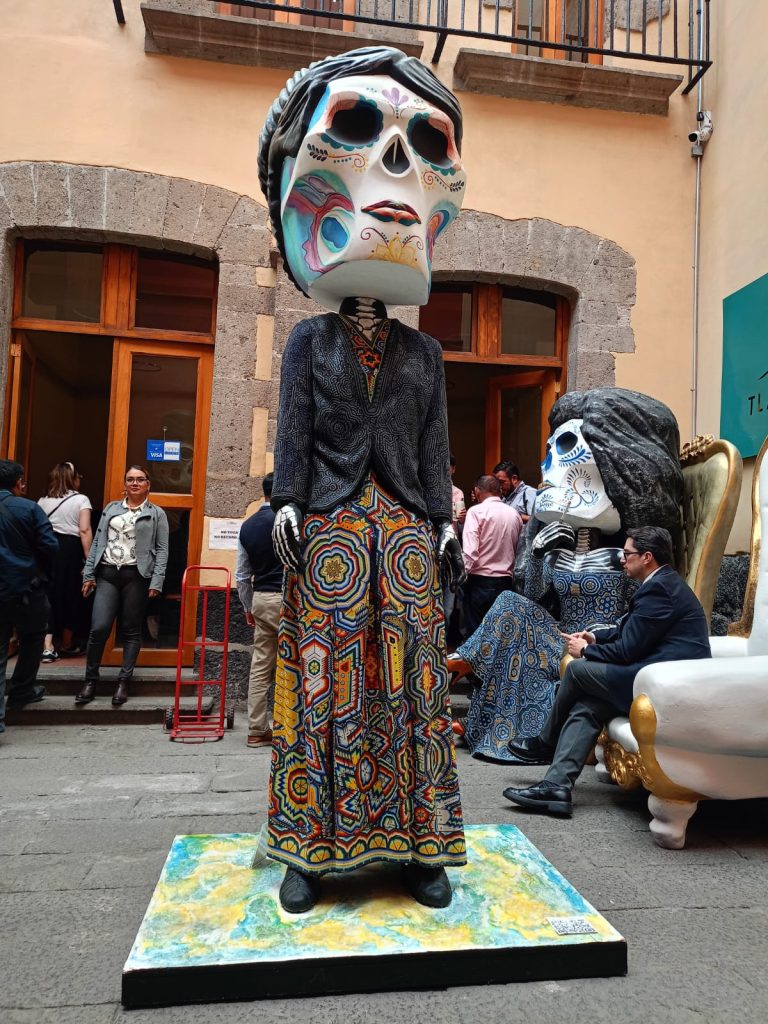 Tamaño de la cabeza de la figura gigante con calaveras coloridas y detalles artísticos en un festival cultural en Tlaxcala, México.