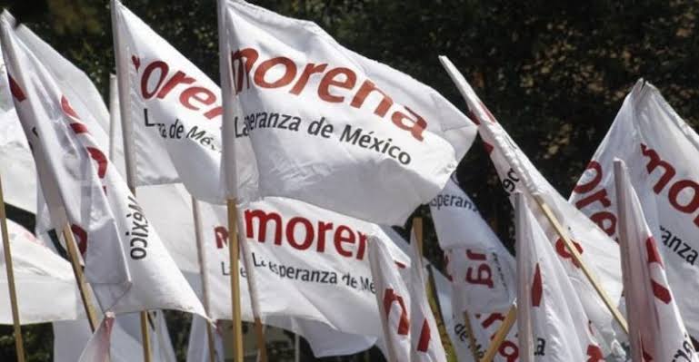 Banderas de Morena con el logo y lema "La esperanza de México" en un evento político en Tlaxcala.