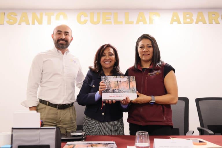 Persona entregando un reconocimiento en una reunión formal, con fondo que dice "SANTO CUELLAR ABAR".