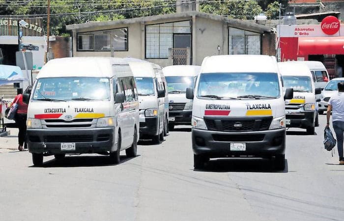 Autobuses de transporte público en Tlaxcala estacionados en una calle, con letreros que indican su destino y el nombre de la ciudad.