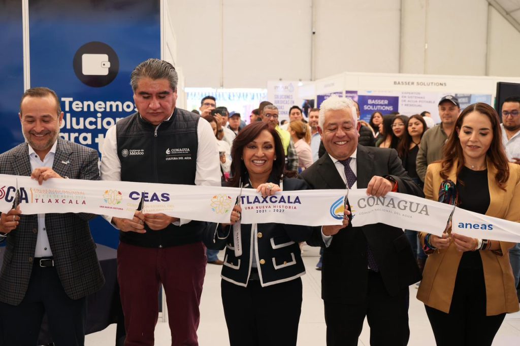 La imagen muestra un grupo de personas en un evento oficial, sosteniendo una cinta de inauguración con logotipos de instituciones de Tlaxcala, en un ambiente de celebración y formalidad.