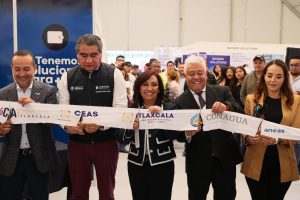 La imagen muestra un grupo de personas en un evento oficial, sosteniendo una cinta de inauguración con logotipos de instituciones de Tlaxcala, en un ambiente de celebración y formalidad.