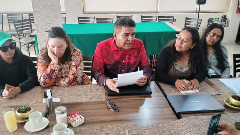 Grupo de personas en una reunión de trabajo en una sala moderna, discutiendo y revisando documentos importantes.
