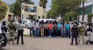 Hombres detenidos por autoridades en una calle de Tlaxcala, rodeados por policías con equipo antimotines, en una escena que indica una operación policial en la ciudad.