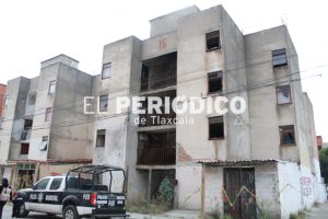 Edificio en construcción o en estado de deterioro en Tlaxcala, con vehículos policiales en el frente y cables eléctricos visibles.