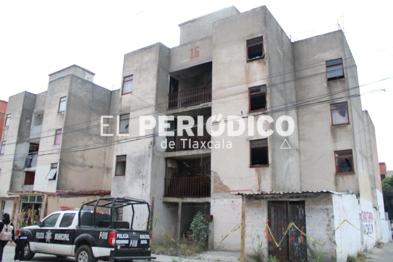 Edificio en construcción o en estado de deterioro en Tlaxcala, con vehículos policiales en el frente y cables eléctricos visibles.