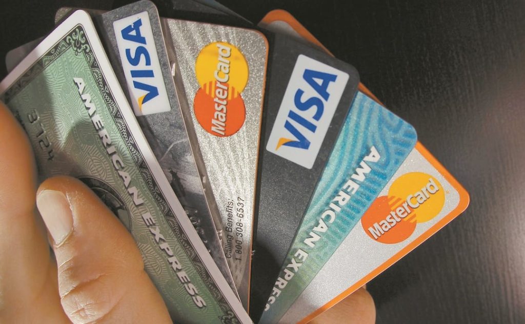 Tarjetas de crédito Visa y Mastercard en mano, mostrando diferentes bancos y tipos de tarjetas para pagos y compras.