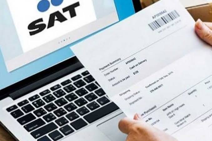 Comprobante de pago del SAT sobre una laptop, con código de barras y detalles visibles, en un entorno de oficina.