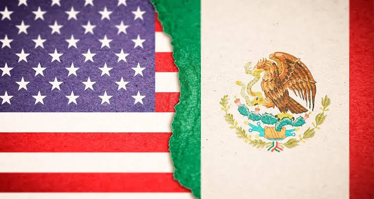 Banderas de Estados Unidos y México fusionadas con un efecto de rasgado en el centro, simbolizando la relación y la historia compartida entre ambos países.