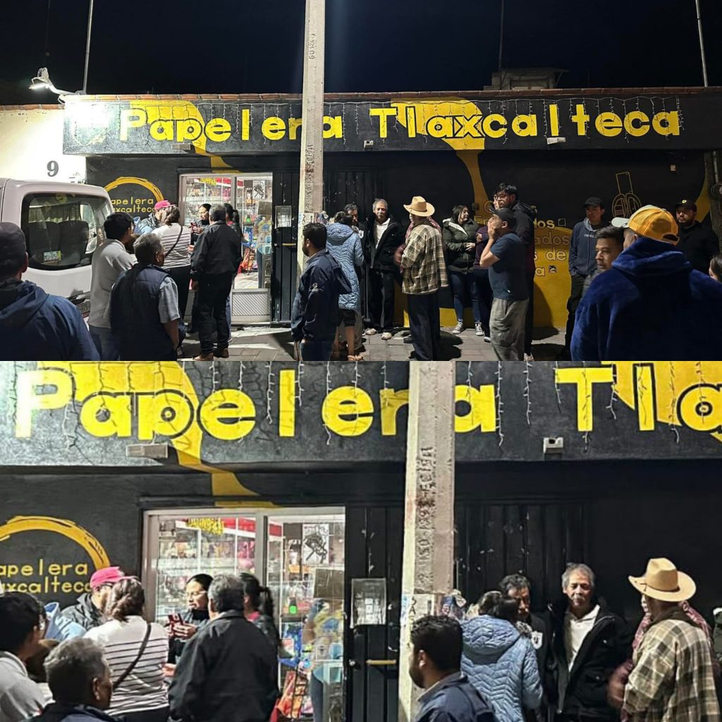 Papelera Tlaxcalteca, tienda de papel y artículos de oficina, con muchas personas haciendo fila y comprando en la tienda, ubicada en un área concurrida, en la noche.