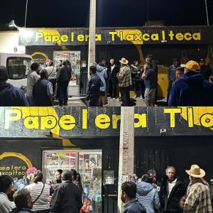 Papelera Tlaxcalteca, tienda de papel y artículos de oficina, con muchas personas haciendo fila y comprando en la tienda, ubicada en un área concurrida, en la noche.